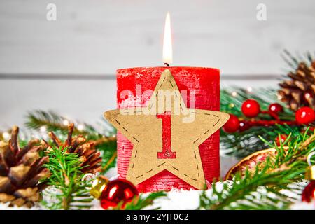 Bayern, Deutschland - 14. November 2024: Erster 1. Adventskerze brennt umgeben von Tannenzweigen, Kegeln und Weihnachtsdekorationen. FOTOMONTAGE *** Erster 1. Adventskerze brennt umgeben von Tannenzweigen, Zapfen und weihnachtliche Dekoration. FOTOMONTAGE Stockfoto