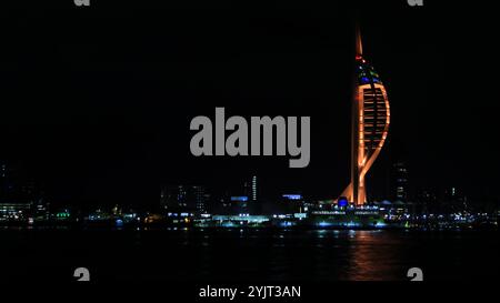 Portsmouth, Hampshire, England. 31. Oktober 2024. Halloween Night: Weitwinkelblick, den Spinnaker Tower mit orangefarbenen Lichtern und anderen Lichtern entlang der Hafenpromenade von Portsmouth. Stockfoto