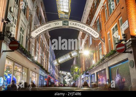 LONDON, UK - 9. November 2024: Ein Blick auf die Carnaby Street zu Weihnachten mit den Dekorationen und Lichtern. Unter den Dekorationen sind Menschen zu sehen Stockfoto