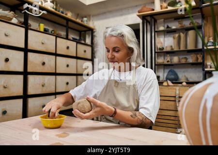 Die talentierte Künstlerin formt Lehm mit fokussierten Händen, eingetaucht in die Freude der Schöpfung in ihrem Atelier. Stockfoto