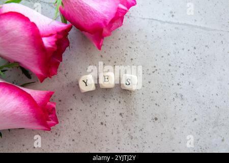 Antwort: Ja. Ausrufewort auf dem Steintisch Hintergrund mit rosa Blumen. Stockfoto