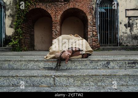 Schwarze Frau, verkleidet als Sklave in Ketten, liegt auf der Treppe einer Straße in Pelourinho. Sklaverei in Brasilien. Darstellung der Sklaven Anastacia. Stockfoto