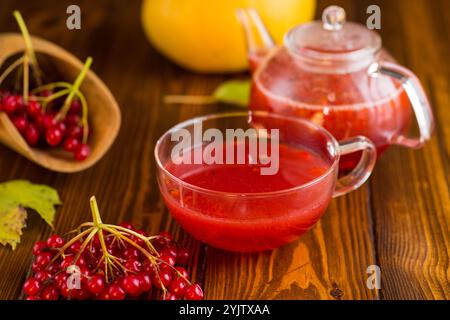 Tee aus reifem roten Viburnum auf einem Holztisch. Stockfoto