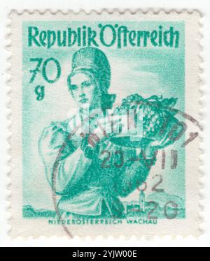 ÖSTERREICH - 1949. März 05: 70 groschene hellblau-grüne Briefmarke mit Frauenbekleidung aus Niederösterreich, Wachau. Eine hübsche Dame hält ein tiefes Tablett mit frischen Trauben Stockfoto