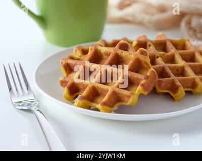 Ein Teller mit selbstgemachten glutenfreien Waffeln auf einem Tisch neben einem Becher und einer Gabel. Nahaufnahme. Stockfoto
