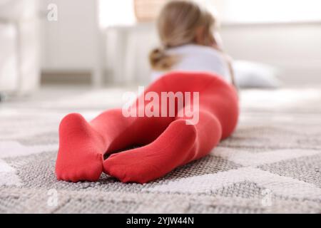 Kind in roten Strumpfhosen zu Hause auf dem Boden, selektiver Fokus Stockfoto