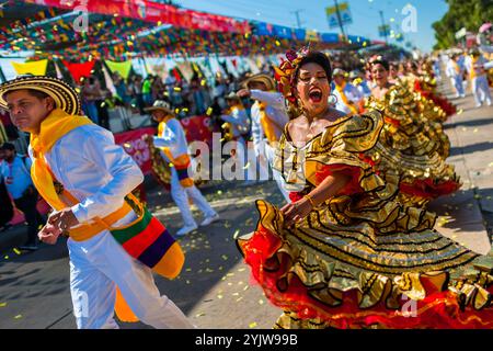 Kolumbianische Paare, die traditionelle Cumbia-Outfits tragen, tanzen die Cumbia während der Parade des Karnevals in Barranquilla, Kolumbien. Stockfoto