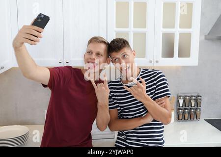 Junge Brüder machen Selfie und zeigen Gesten in der Küche Stockfoto