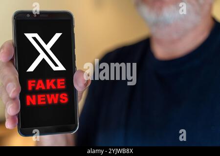 15. November 2024: Smartphone zeigt das Logo von Plattform X und die Warnung FAKE NEWS. Symbolisches Image für die Verbreitung von Fehlinformationen in sozialen Medien. FOTOMONTAGE *** Smartphone zeigt das Logo der Plattform X und die Warnung FAKE NEWS. Symbolbild für die Verbreitung von Fehlinformationen in sozialen Medien. FOTOMONTAGE Stockfoto