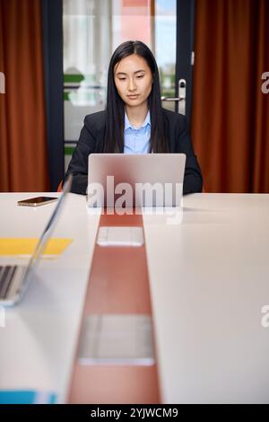 Asiatische Frau, die an einem modernen Laptop arbeitet Stockfoto