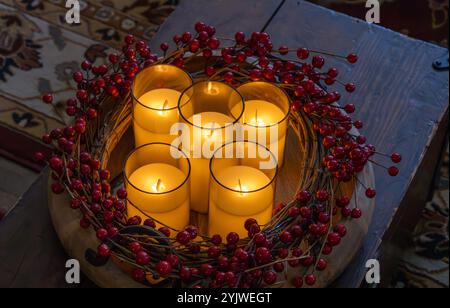 Vollbild-Nahaufnahme der Textur von sanft leuchtenden künstlichen Kerzen in Glasgläsern, umgeben von Weihnachtsgirlande Stockfoto