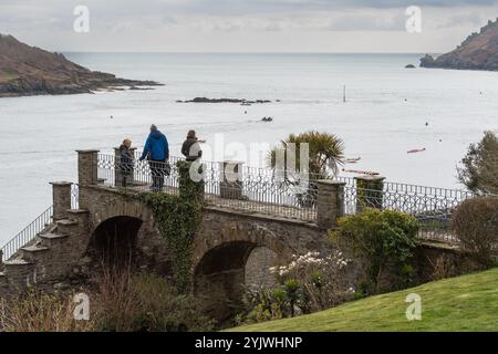 Die Familie steht auf einer privaten Fußgängerbrücke, mit kunstvollen Schienen, über der Cliff Road und bietet an einem grauen Frühlingstag den Blick auf die Mündung von Salcombe Stockfoto