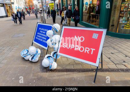 Leeds, Großbritannien. NOVEMBER 2024. Schilder auf der Albion Street „Wir entschuldigen uns für die Unannehmlichkeiten, die während der Suizidkrise entstanden sind“ und „No Support“, während Schilder und Helme im Rahmen von „Project 7000, the Lost City“ in Leeds auftauchten, einer visuellen Kampagne, um eine Stadt zu zeigen, die nie gebaut werden würde, da die 7000 Bauarbeiter, die sie bauen würden, an Selbstmord gestorben sind. Eine Reihe von Bauunternehmen unterstützten das Projekt, bei dem 7000 Helme in Großbritannien aufgestellt wurden. Credit Milo Chandler/Alamy Live News Stockfoto