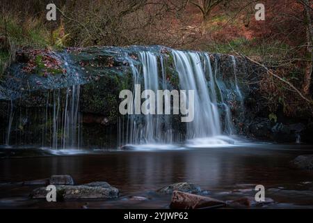 Wasserfall, der über moosige Felsen im Herbstwald stürzt und eine entspannende Atmosphäre schafft Stockfoto