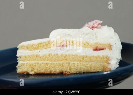 Ein kleiner japanischer Erdbeerkuchen auf einem stilvollen japanischen Teller auf einem schwarzen Tuch auf einem weißen Tisch. Stockfoto