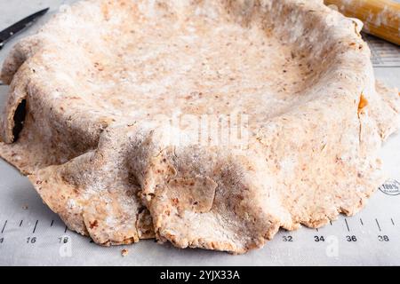 Ausgerollte Pecan Shortbread Pie Crust über einer Pie Pan Close-up: Tortenkrustteig aus dünn gerollten Nüssen, die über eine Tortenplatte gelegt werden Stockfoto