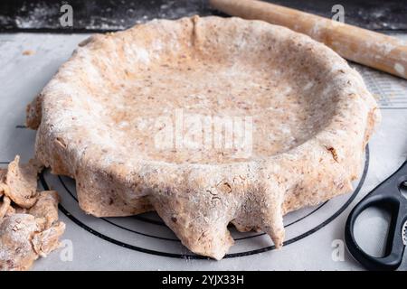 Ausgerollte Pecan Shortbread Pie Kruste über einer Pie Pan angewinkelte Ansicht: Tortenkrustteig aus dünn gerollten Nüssen, die über eine Tortenplatte gelegt werden Stockfoto