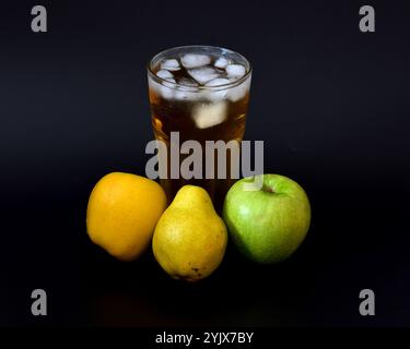 Apfel- und Birnensaft in einem hohen Glas mit Eis auf schwarzem Hintergrund, neben Reifen Früchten. Nahaufnahme. Stockfoto