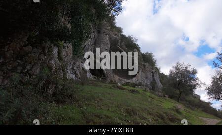 Buracas do Casmilo in Condeixa - Portugal. Alte Kalksteinhöhlen in einem zerklüfteten Hügel mit mehreren natürlichen Höhlenöffnungen im Grün Stockfoto