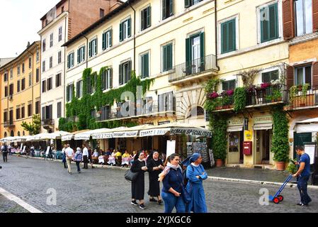 Rom, Italien - 9. Mai 2018: Menschen, einschließlich römisch-katholischer Nonnen, laufen auf der Kopfsteinpflasterstraße an den Restaurants entlang des historischen Pia vorbei Stockfoto