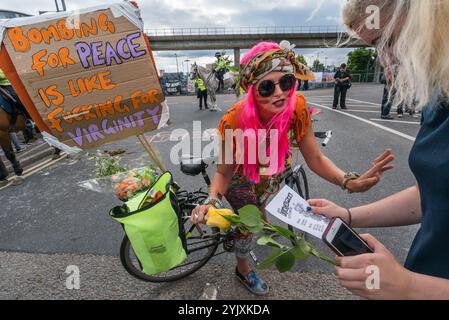 London, Großbritannien. September 2017. Mehrere hundert Demonstranten nehmen an einem Festival am Osttor der weltweit größten Waffenmesse, DSEI, Teil, der Defence & Security Equipment International, die von der britischen Regierung unterstützt wird, wo Waffenfirmen und Waffenhändler Waffen an Länder auf der ganzen Welt verkaufen, einschließlich vieler repressiver Regime. Eine Frau mit einem Fahrrad verteilt Flyer, die Leute einladen, zu einem Flashmob gegen DSEI am Montagmorgen zu kommen. Stockfoto