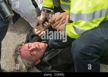 London, Großbritannien. September 2017. Die Polizei verhaftet einen Mann, der unter den Rädern eines Lastwagens lag, beim Festival of Resistance am Osttor der größten Waffenmesse der Welt, DSEI. Die internationale Messe für Defence & Security Equipment wird von der britischen Regierung unterstützt und ist eine Veranstaltung, auf der Rüstungsunternehmen und Waffenhändler Waffen an Länder auf der ganzen Welt verkaufen, einschließlich vieler repressiver Regime. Die Demonstranten hatten einen Lastwagen gestoppt, der in die Show ging, mit einer Sperre und einem Quäker-Treffen auf der Straße. Die Polizei versuchte, die Straße freizumachen und nahm mehrere Festnahmen vor, einschließlich der beiden, die an der Sperre beteiligt waren. Stockfoto