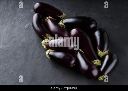 Haufen reifer frischer Auberginen auf dunklem Hintergrund, Bio-ökologisches Essen von lokalen Bauern, Top View Stockfoto
