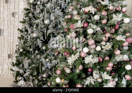 Weihnachtsbaum mit Spielzeug in Silber und Rosa. Darin sehen wir die Ballons mit Bändern und Lichtern glühende Girlande. Stockfoto