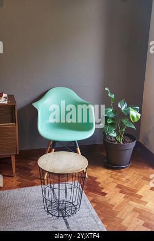 Wohnzimmer mit grünem Stuhl, Holzkommode und Pflanzen in einem Blumentopf Stockfoto