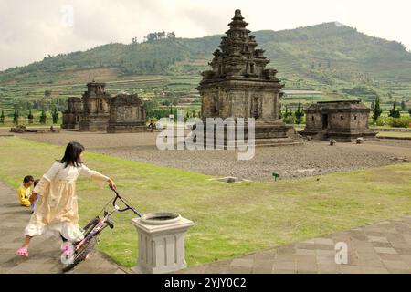 Kinder haben Freizeit im archäologischen Park des Arjuna-Tempels auf dem Dieng-Plateau, der sich administrativ in Dieng Kulon, Batur, Banjarnegara, Zentraljava, Indonesien befindet. Stockfoto