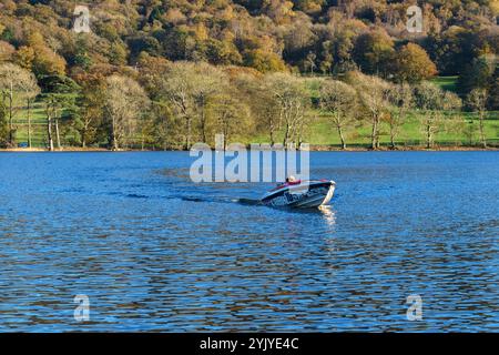 Ein Motorboot auf Coniston Water mit seinem Bug in der Luft gleitet an einem hellen Herbsttag A während der Coniston Power Boat Records Woche über den See. Stockfoto