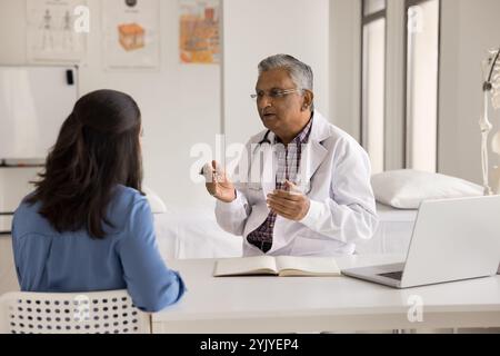 Indischer männlicher Arzt fragt Patienten über Symptome während des Besuchs Stockfoto