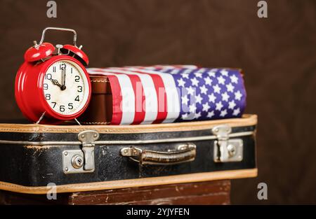 Wecker mit Koffer und Flagge. US-Staatsbürgerschaft, Migrationshintergrund mit Kopierraum. Stockfoto