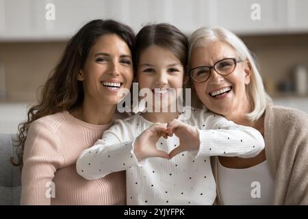 Liebevolles kleines Mädchen posiert für die Kamera mit Mom und Oma Stockfoto