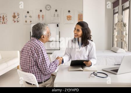 Freundliche Kardiologin im Fell, die Hände schütteln, ältere Patienten grüßen Stockfoto