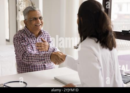 Ältere Patientin und junge Hausärztin beim Händeschütteln Stockfoto