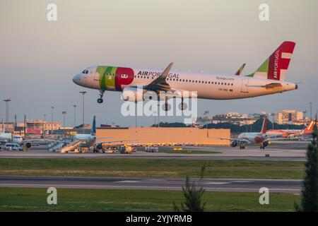 Tap Air portugal der airbus a320 landet bei Sonnenuntergang auf dem internationalen Flughafen lissabon humberto delgado, während Passagiere im Hintergrund ein anderes Flugzeug besteigen Stockfoto