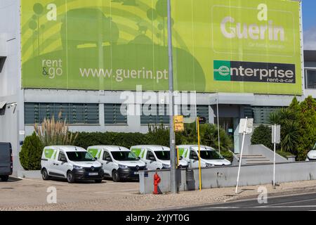 Weiße Lieferwagen, die vor guerin geparkt sind, und Unternehmen mieten ein Auto-Bürogebäude mit Firmenbranding und Werbung auf einem großen grünen Banner Stockfoto