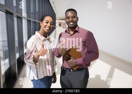 Positive junge afroamerikanische Geschäftskollegen zeigen den Daumen hoch Stockfoto