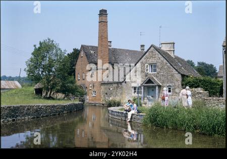 Mill Cottage, Mill Lane, Lower Slaughter, Cotswold, Gloucestershire, 1987. Mill Cottage and Slaughter Mill von Süden aus gesehen, mit Besuchern am River Eye im Vordergrund. Stockfoto