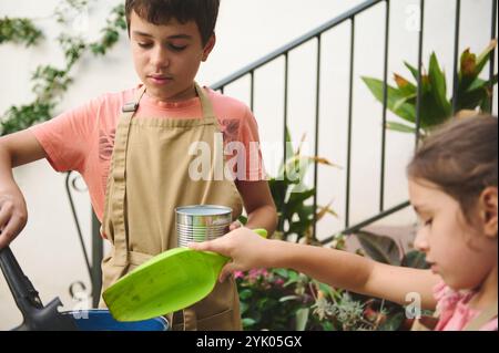 Zwei Kinder, die Schürzen tragen, genießen eine Gartenarbeit und lernen in einer lustigen Umgebung mehr über Pflanzen und Teamarbeit. Stockfoto