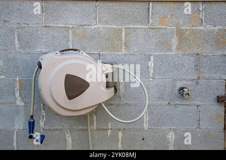 Blockieren Sie die Wand mit Schlauchtrommel und Wasserhahn Stockfoto