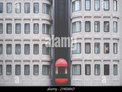 Ein markanter Red External Lift (Aufzug) an Einem Gebäude im Stil der Brutalistischen Arhitecture Stockfoto