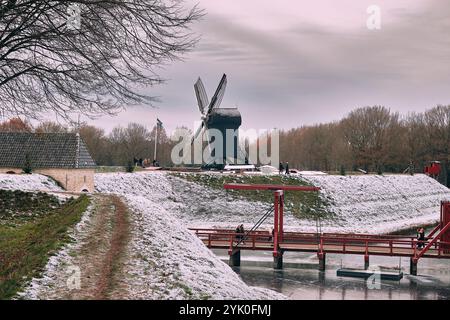 Ein Winterblick auf den Burggraben der Bourtange mit einer historischen Zugbrücke und Windmühle, umgeben von schneebedeckten Landschaften und Weihnachtsmarkt Stockfoto