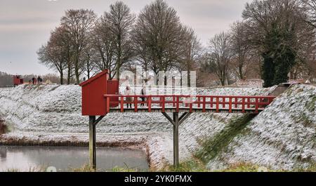 Ein Winterblick auf den Burggraben der Bourtange mit einer historischen Brücke zur Toilette, umgeben von schneebedeckten Landschaften und Weihnachtsmarkt-Besuchern Stockfoto