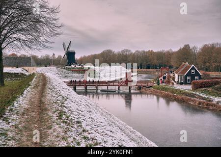 Ein Winterblick auf den Burggraben der Bourtange mit einer historischen Zugbrücke und Windmühle, umgeben von schneebedeckten Landschaften und Weihnachtsmarkt Stockfoto