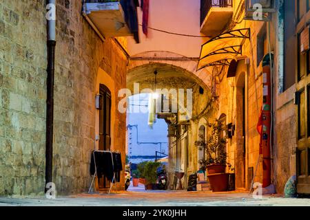 Eine enge Gasse in Bari Vecchia, Italien, beleuchtet von warmen Straßenlaternen Stockfoto