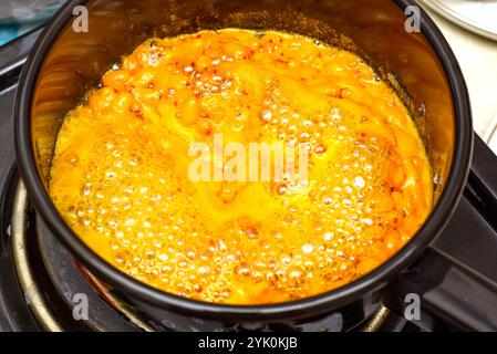 Kochende Sanddornbeeren mit Kristallzucker in einem Topf zur Herstellung von Marmelade. Hausmannskost. Stockfoto