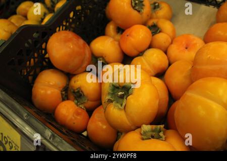 Persimmonen der Sorte Kaki, flache Persimmonen aus der Nähe. Obst der Saison im Laden. Stockfoto