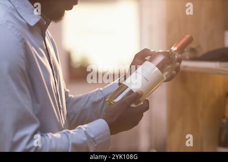 Mittlere Nahaufnahme eines nicht erkennbaren afroamerikanischen Mannes, der eine Flasche teuren Weins hält Stockfoto